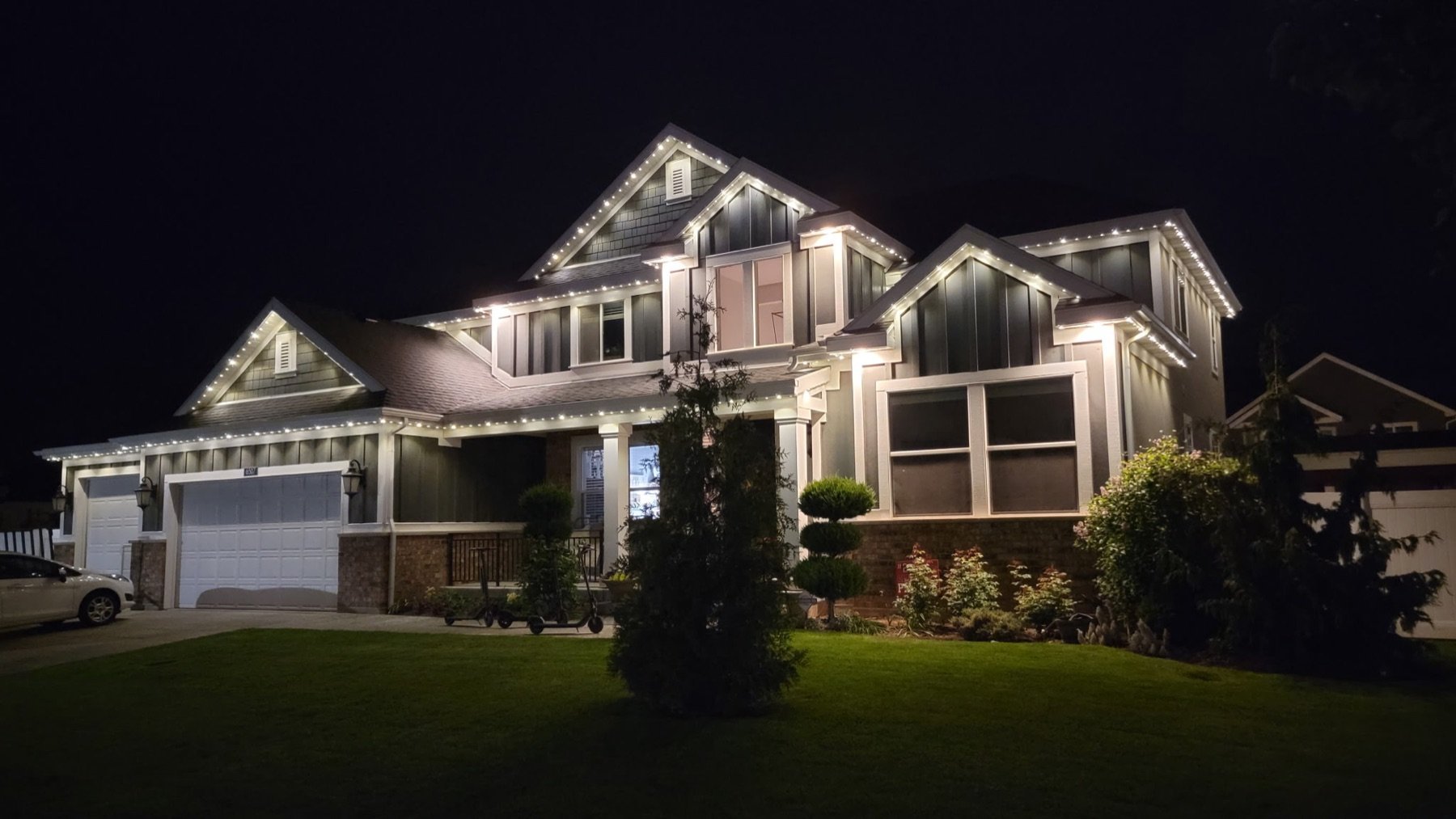 White roofline lighting across a home and garage at night