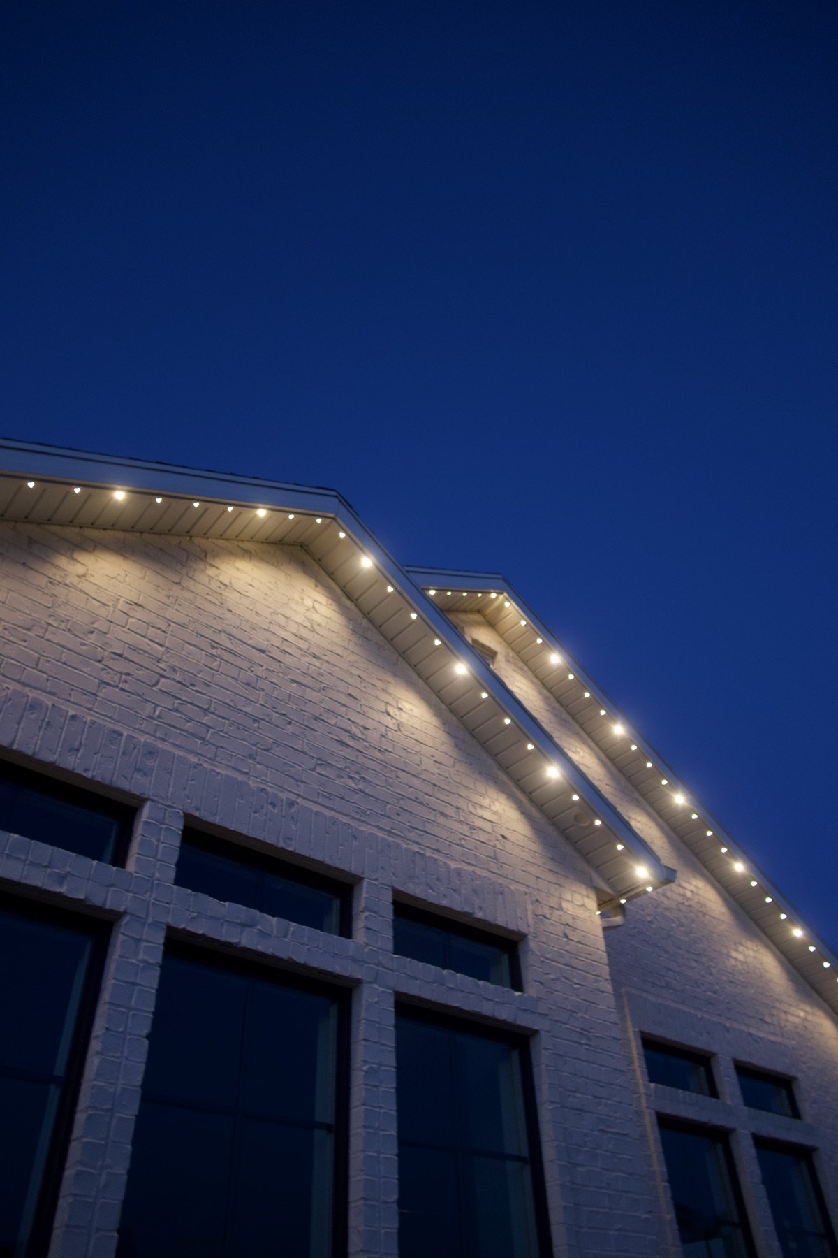 Warm white lights tracing a garage roof at dusk