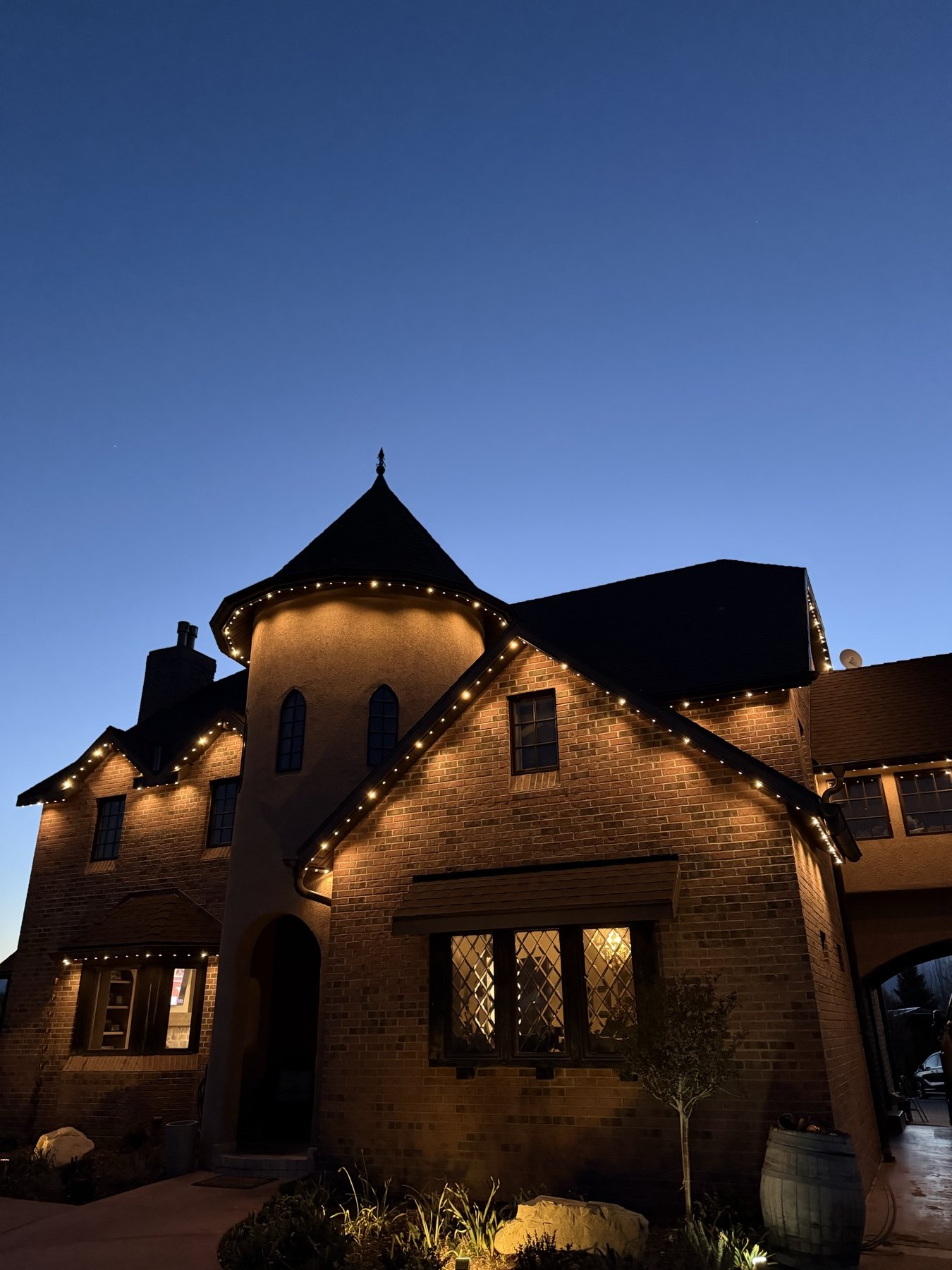 Warm white lighting on a brick home with a turret