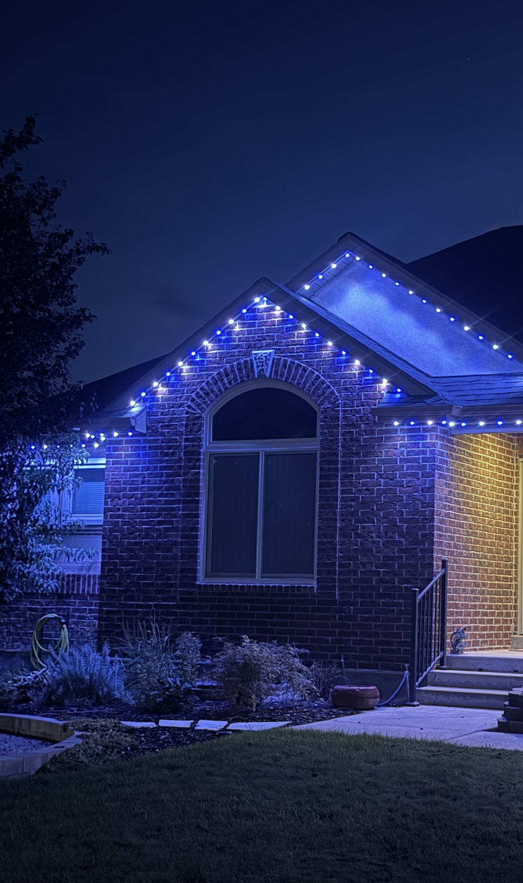 Blue roofline lighting on a brick home at dusk