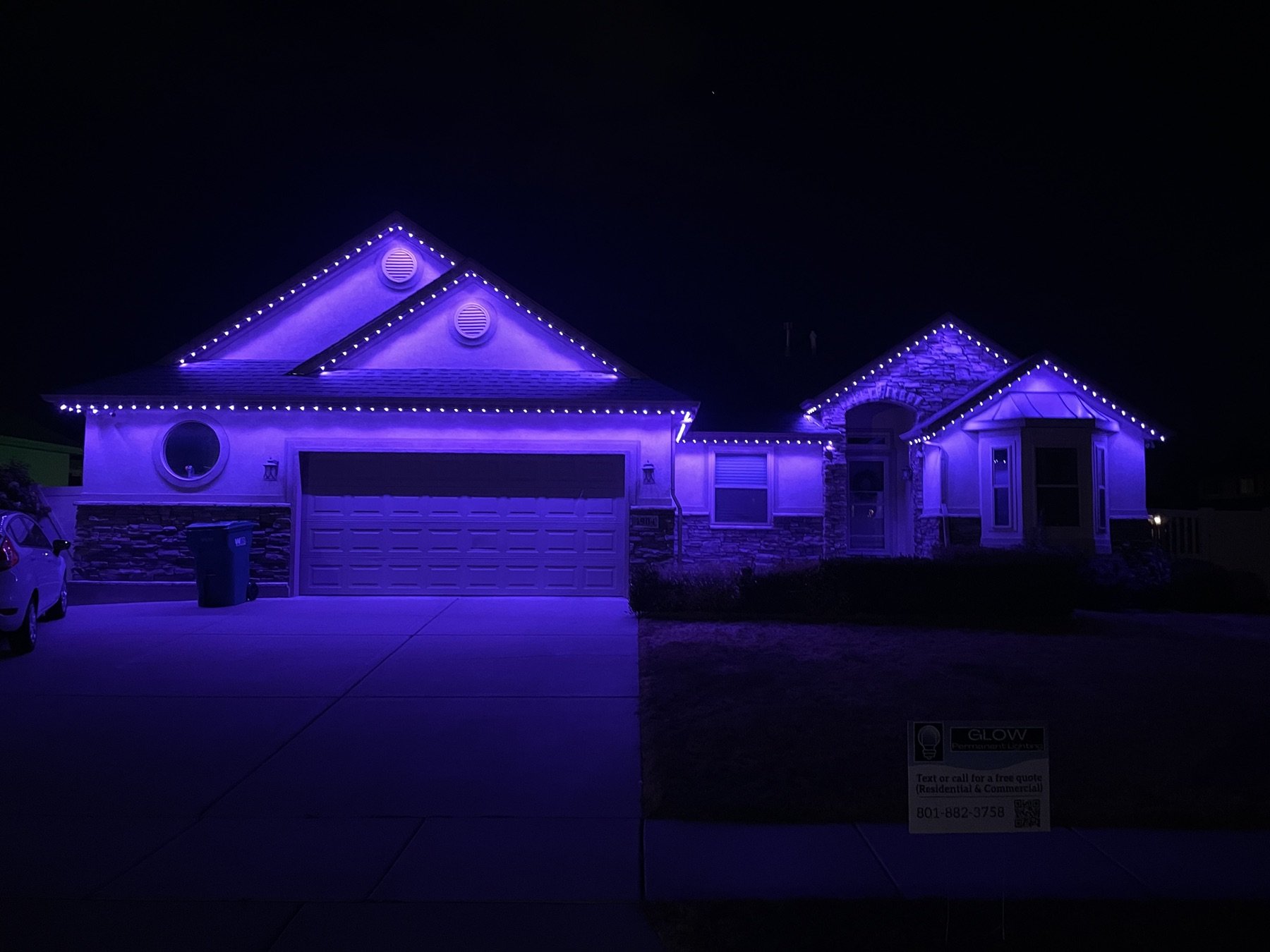 Purple roofline lighting across a home and garage at night