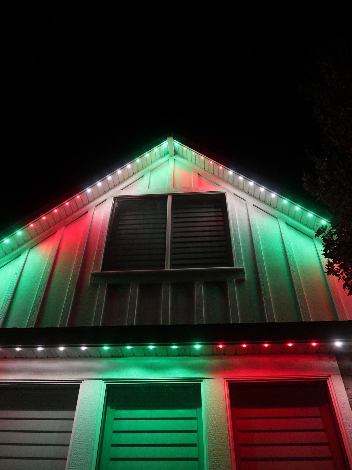 Red and green holiday lights beside a porch